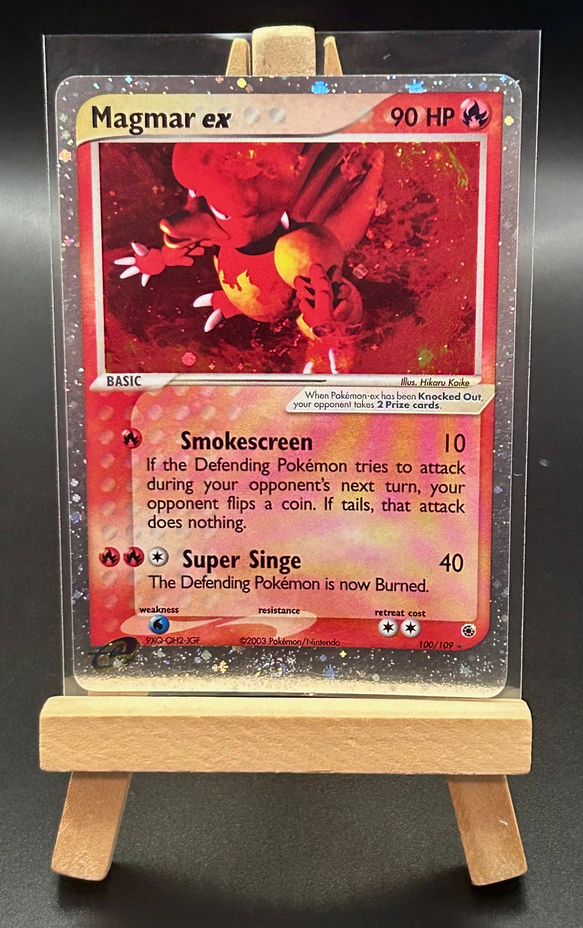 Pokémon trading card featuring Magmar ex on a clear stand with a dark background