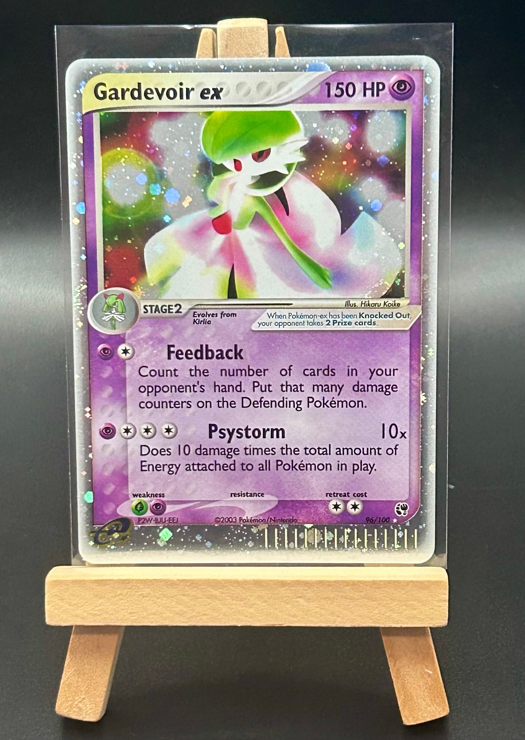Pokémon trading card featuring Gardevoir ex on a clear stand with a wooden base.
